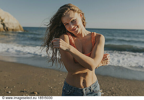 Smiling woman standing at beach on sunny day
