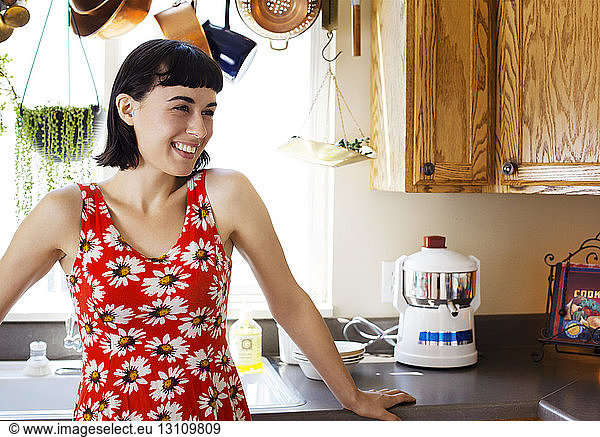 Smiling woman standing at kitchen counter in home
