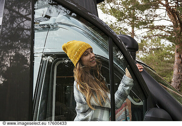Smiling woman standing at open van door