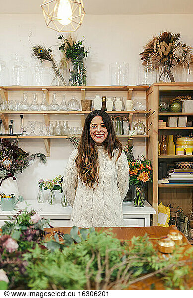 Smiling woman standing by table at flower shop