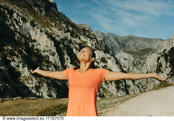 Smiling woman standing with arms outstretched at Cares Trail in Picos De Europe National Park  Asturias  Spain