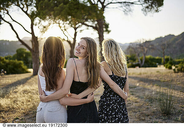 Smiling woman standing with friends in park on weekend