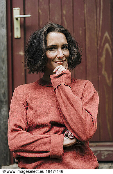 Smiling woman standing with hand on chin
