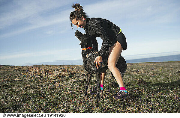 Smiling woman stroking dog on grass