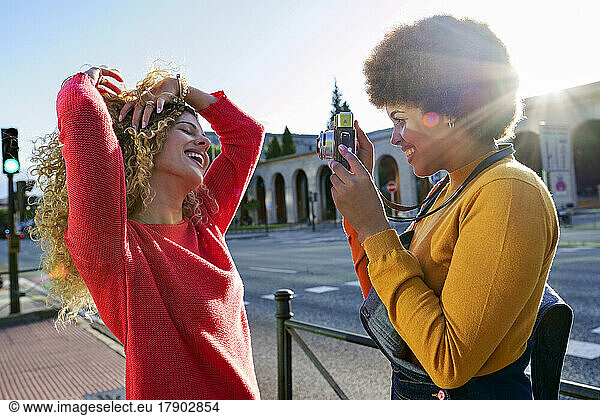 Smiling woman taking pictures of girlfriend through camera