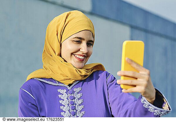 Smiling woman taking selfie through mobile phone
