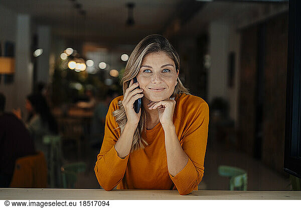 Smiling woman taking through smart phone in cafe
