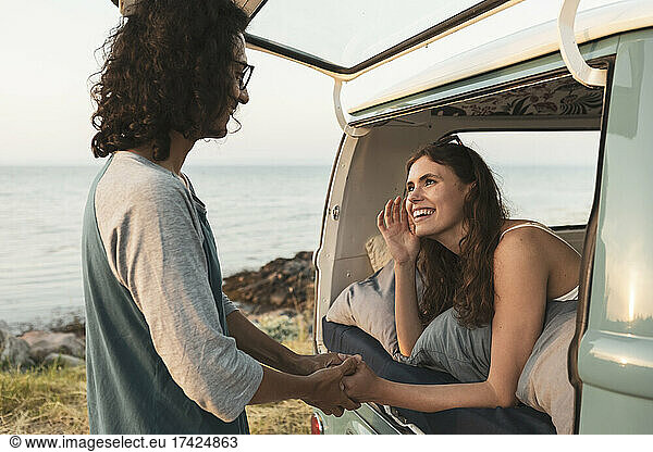 Smiling woman talking with male friend at seashore
