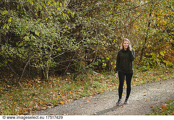 Smiling woman talks on phone while walking wooded trail