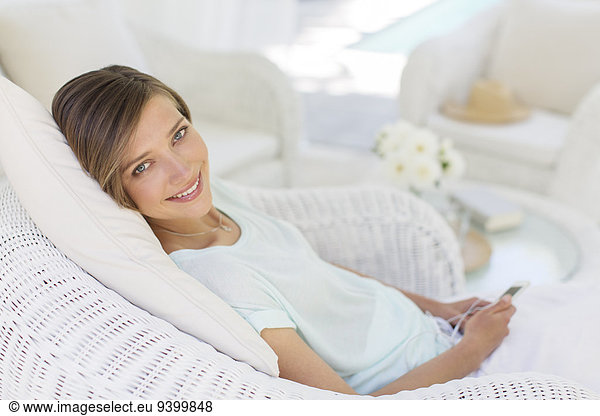 Smiling woman using cell phone in wicker chair