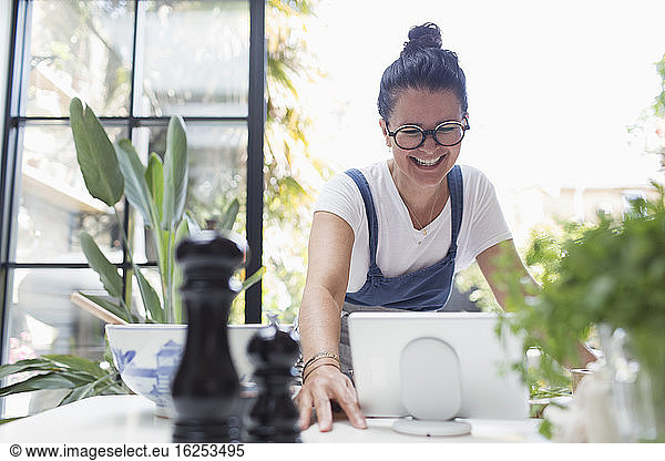 Smiling woman using digital tablet at dining table