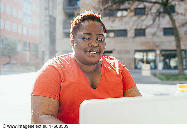 Smiling woman using laptop on sunny day