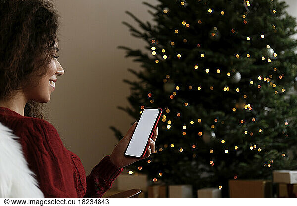 Smiling woman using mobile phone at home