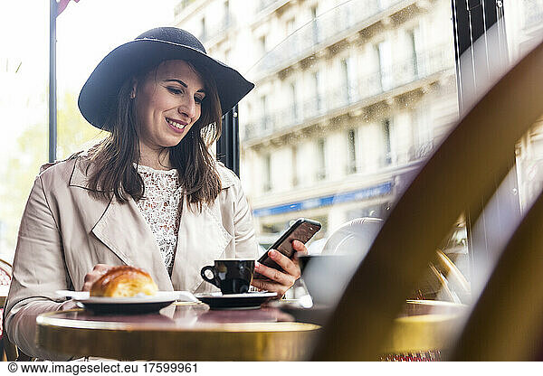 Smiling woman using mobile phone in cafe