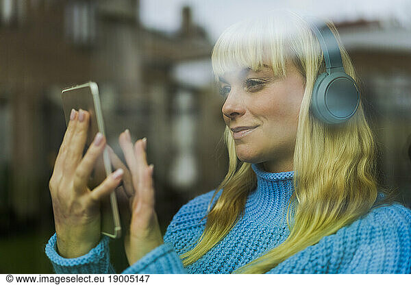 Smiling woman using tablet PC seen through glass