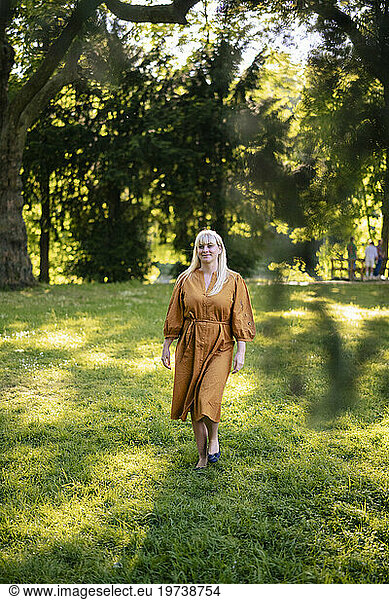 Smiling woman walking on grass in park