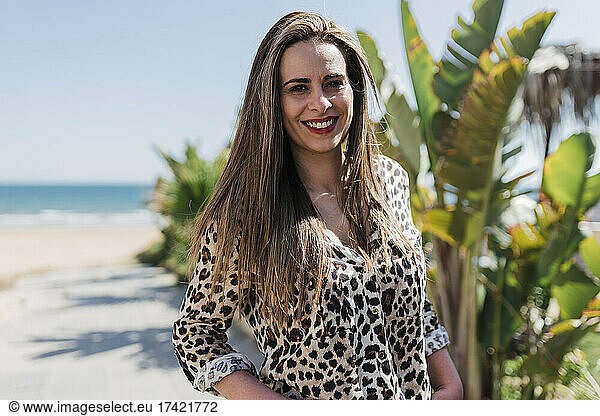 Smiling woman wearing Cheetah print shirt at beach on sunny day