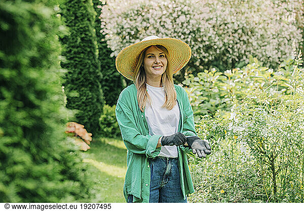 Smiling woman wearing gloves in garden