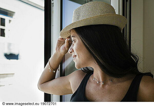 Smiling woman wearing hat looking through window