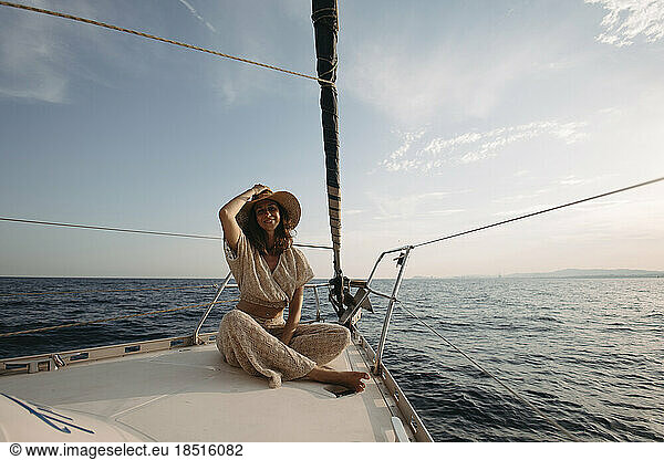 Smiling woman wearing hat sitting on sailboat