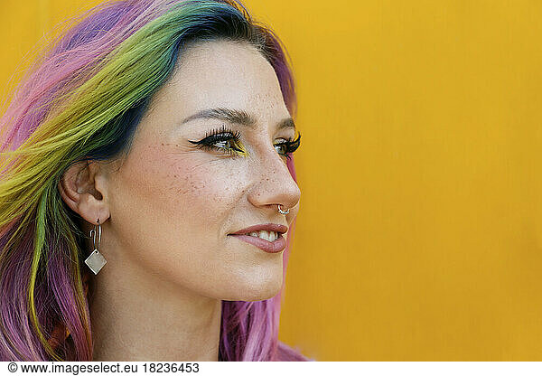 Smiling woman wearing nose ring in front of yellow wall