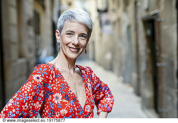 Smiling woman wearing red dress standing in alley