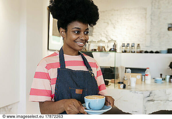 Smiling woman with Afro hairstyle holding coffee cup