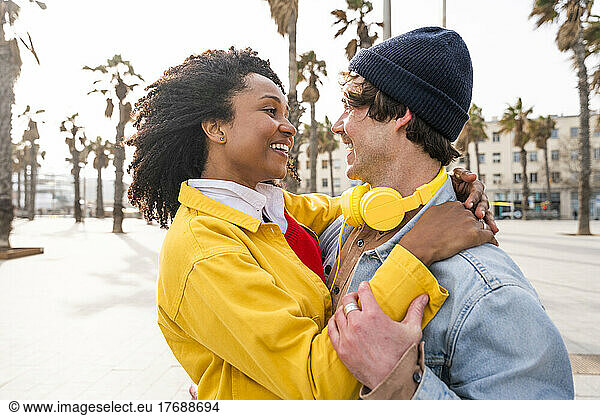 Smiling woman with Afro hairstyle looking at man wearing knit hat
