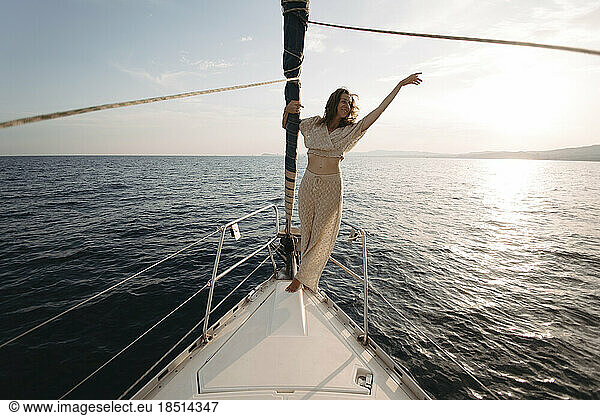 Smiling woman with arm raised enjoying on sailboat