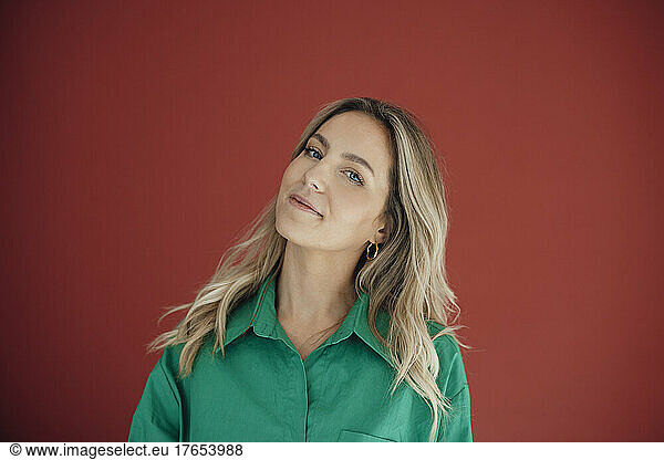Smiling woman with blond hair against red background