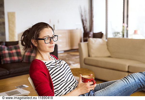 Smiling woman with cup of coffee relaxing at home