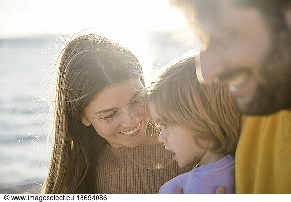 Smiling woman with daughter at beach on sunny day