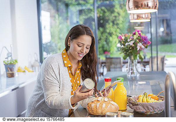 Smiling woman with digital tablet baking in kitchen