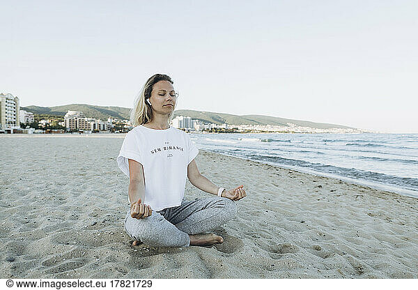 Smiling woman with eyes closed meditating at beach
