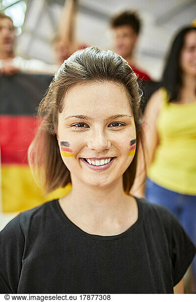 Smiling woman with German Flag painted on face at sports event in stadium