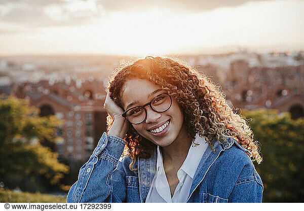 Smiling woman with hand in hair during sunset