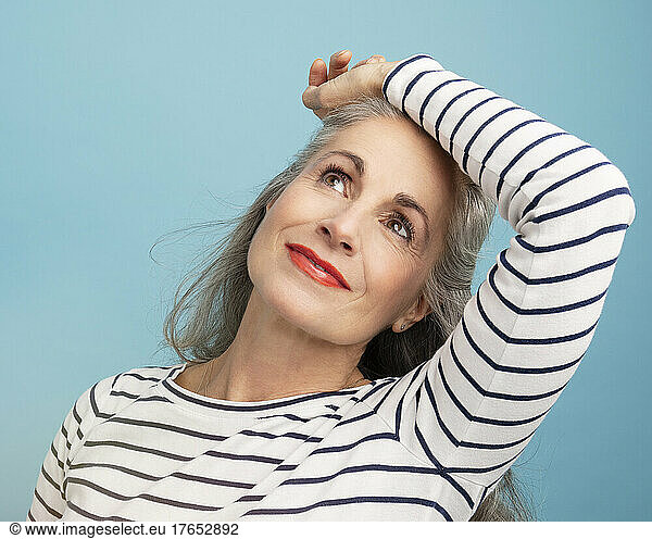 Smiling woman with hand on head against blue background