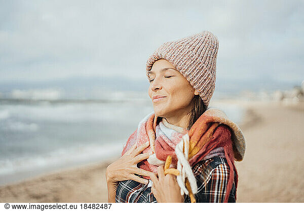 Smiling woman with hands on chest at beach