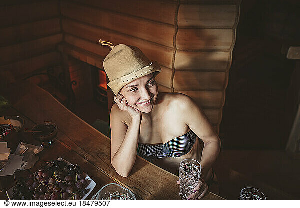 Smiling woman with hat day dreaming in sauna