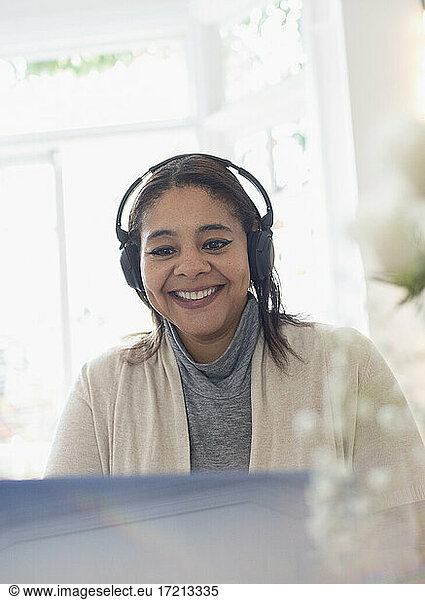 Smiling woman with headphones working from home at laptop