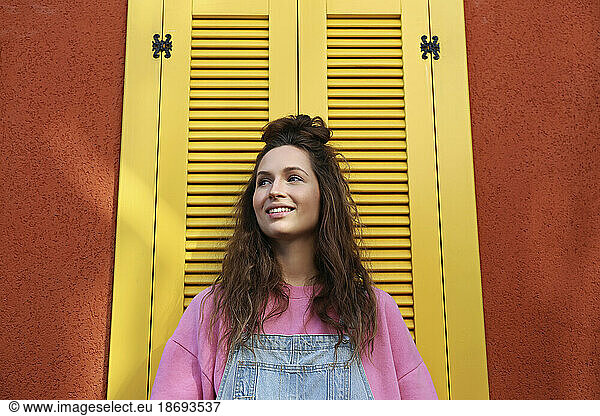 Smiling woman with long hair near wall with yellow windows