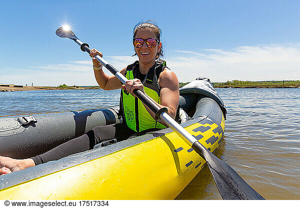Smiling Woman with Paddle in Yellow Kayak on the Water in New England