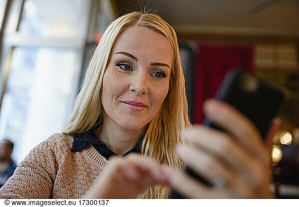 Smiling woman with phone in cafe