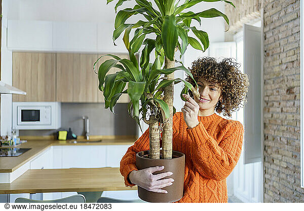 Smiling woman with potted plant at home