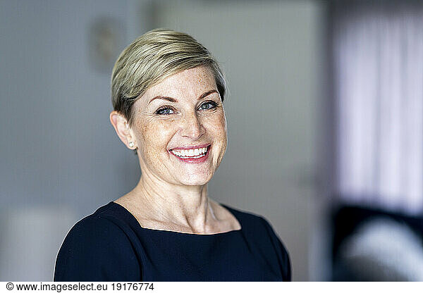 Smiling woman with short blond hair at home