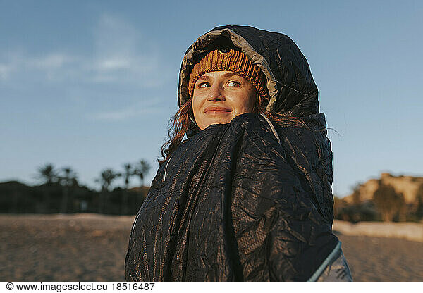 Smiling woman with sleeping bag at beach
