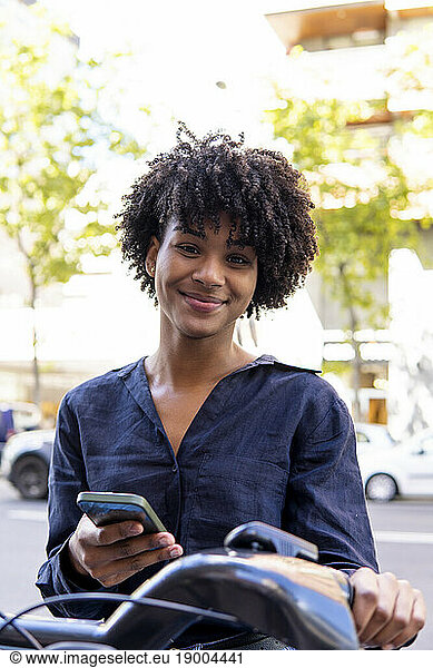 Smiling woman with smart phone and electric bicycle