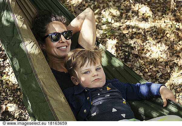 Smiling woman with son relaxing in hammock