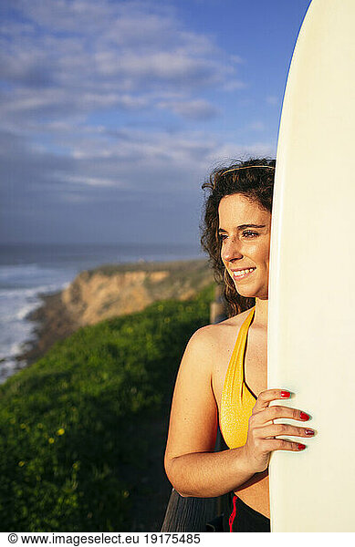 Smiling woman with surfboard on sunny day at beach