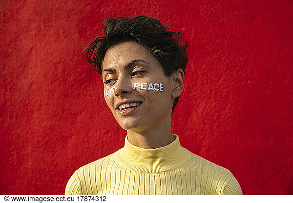 Smiling woman with text on face in front of red wall